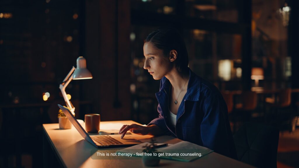 A woman is sitting at the desk surfing her laptop. Background is dimmed.