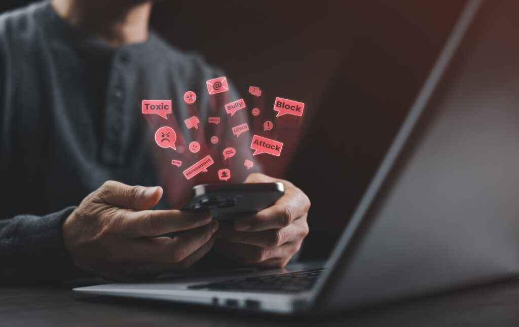 cyberbullying and online harassment concept. person holding phone with toxic, bullying messages in dark mood lighting.